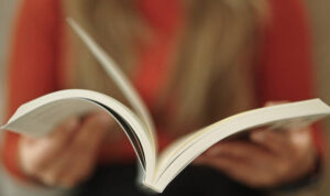 Close-up hand of woman reading and open book page.