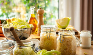 Homemade sauerkraut in glass jars and fresly shredded cabbage on kitchen table