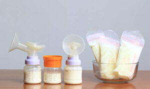 Bottles and frozen breast milk storage bags for new baby on wooden table